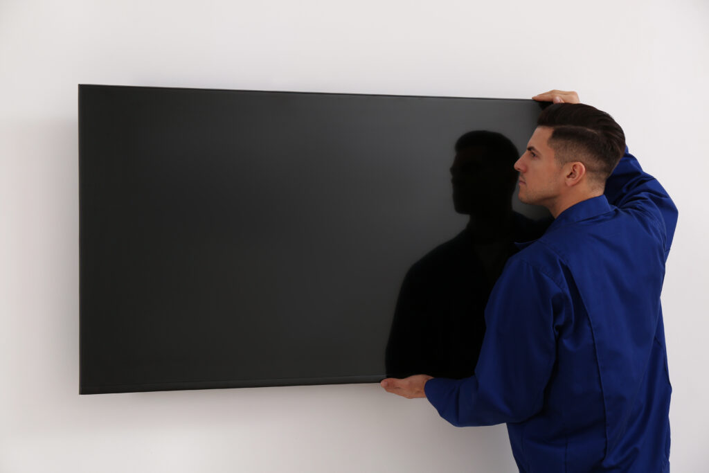 Installing Your Digital Signage - Professional technician installing modern flat screen TV on wall indoors
