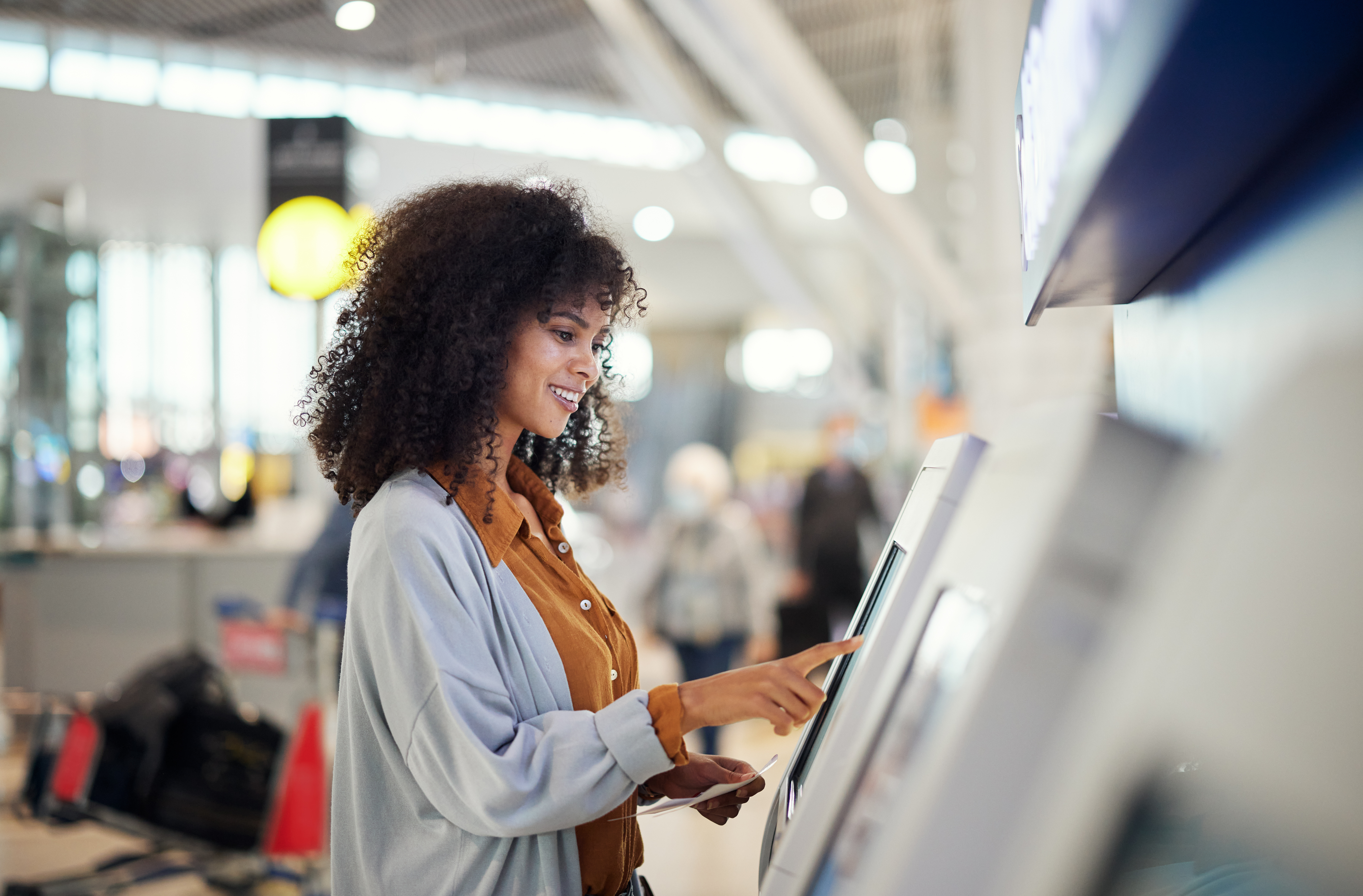 kiosk software Black woman, airport and smile by self service station for ticket, registration or boarding pass. Happy African female traveler by kiosk machine for travel application, document or booking flight